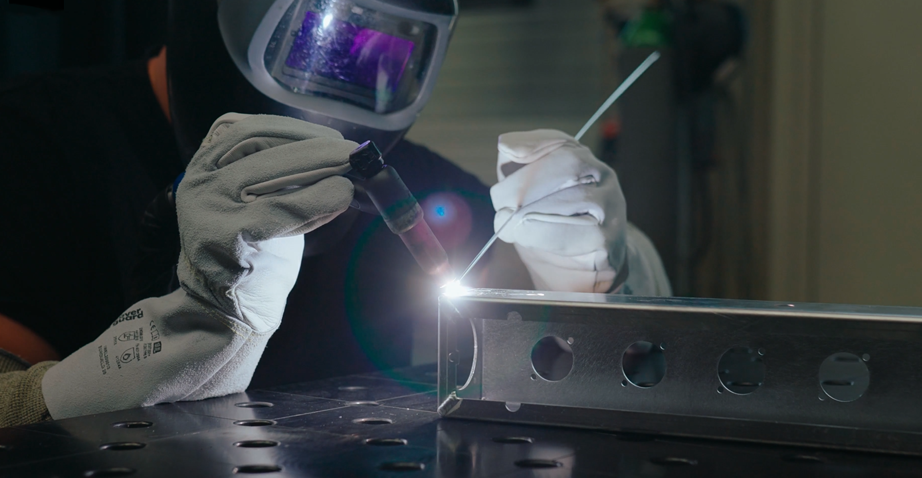 Welder TIG welding a metal PDU housing with socket cut-outs
