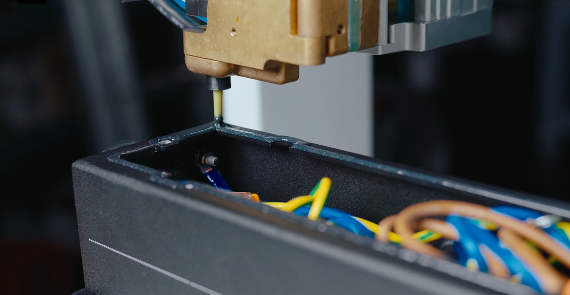 Automated dispenser applying a sealing bead to a wired PDU enclosure