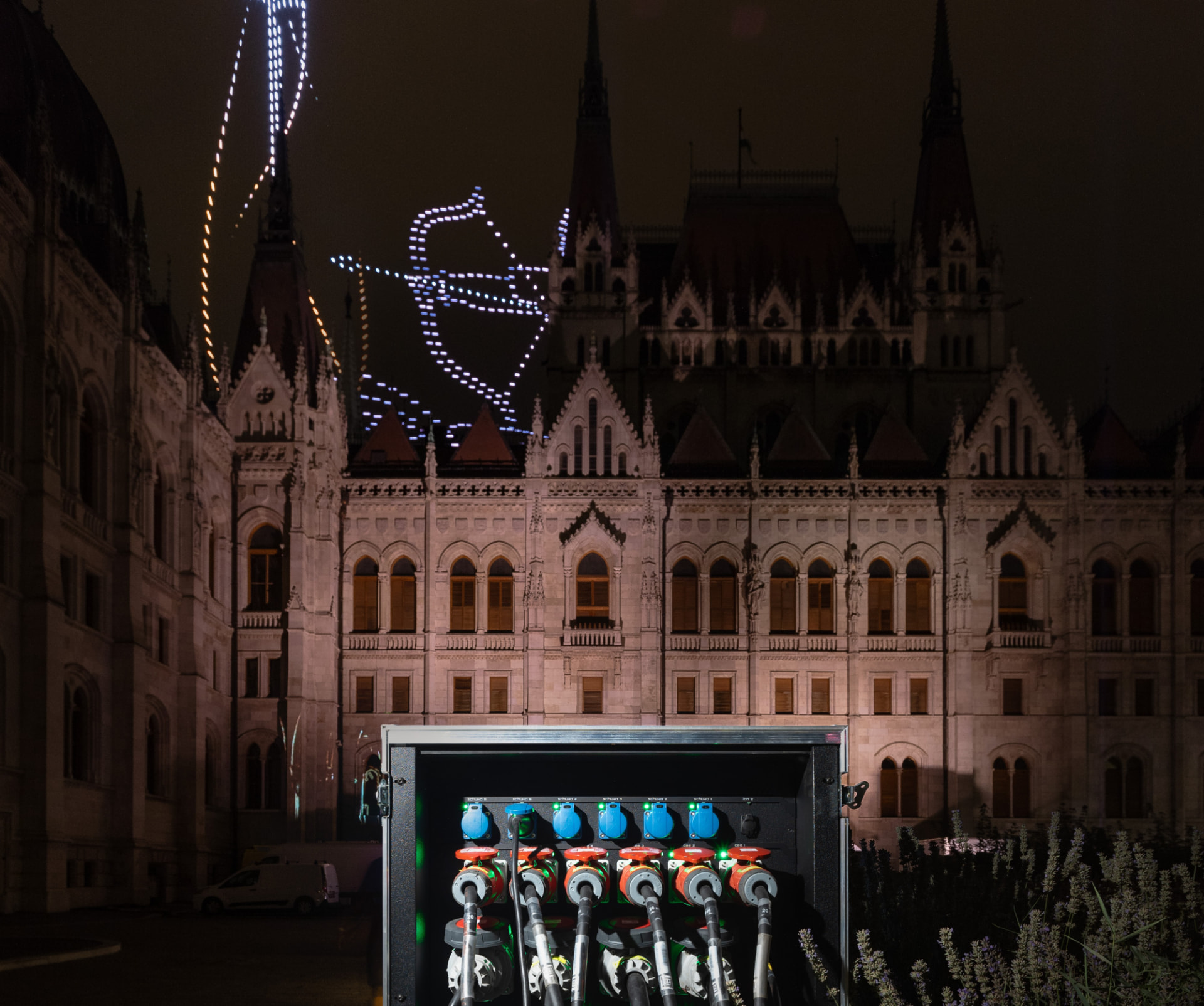 Open Tesla Tech flightcase PDU with connected CEE and Schuko outlets in front of the illuminated Hungarian Parliament at night