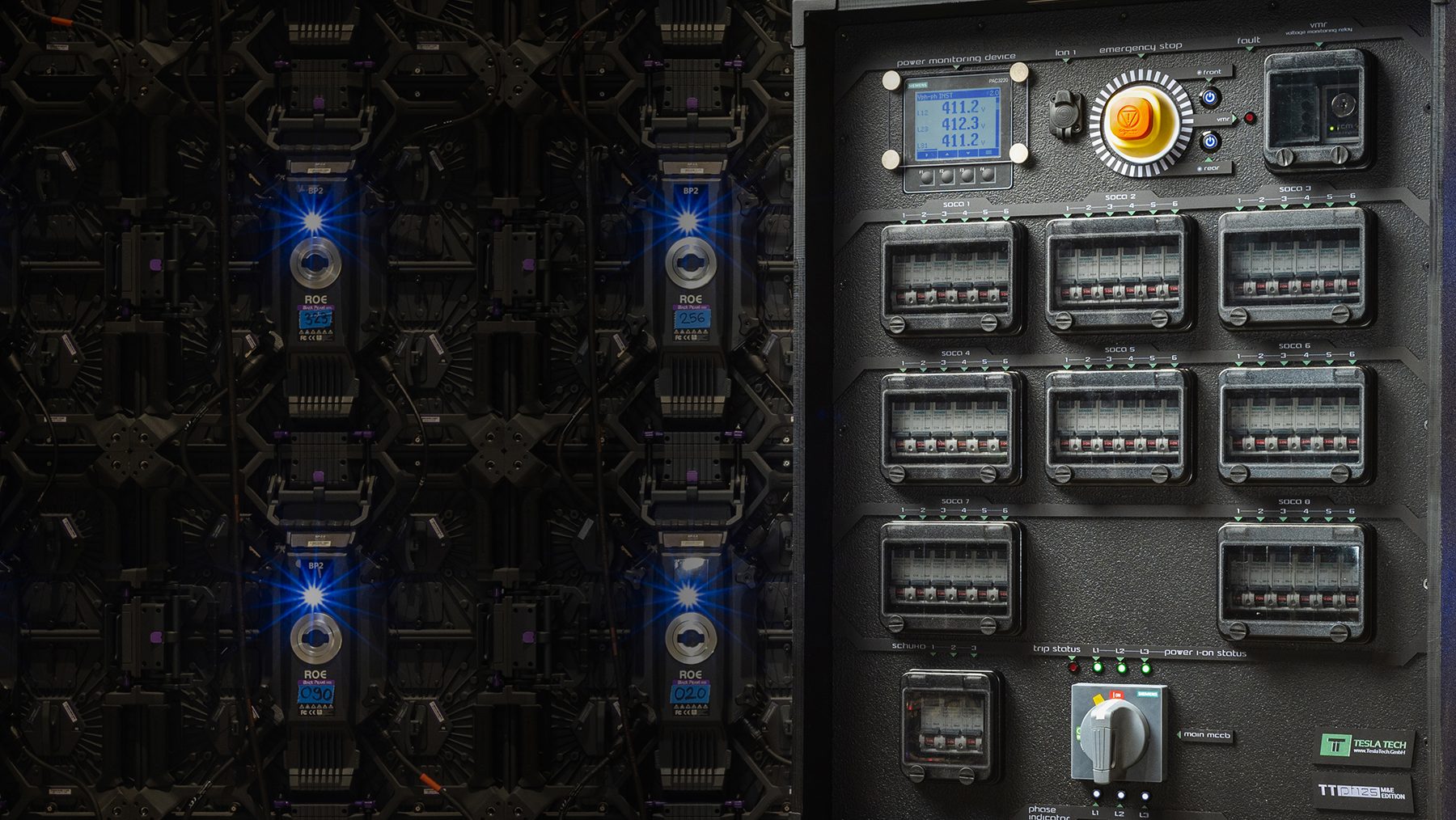 Front of a Tesla Tech PDU with a power monitor, emergency stop and circuit breaker windows.